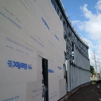 Exterior sheathing installation is underway along the north elevation.