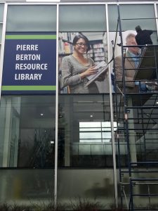 Placing the colourful film on Pierre Berton Resource Library's windows.