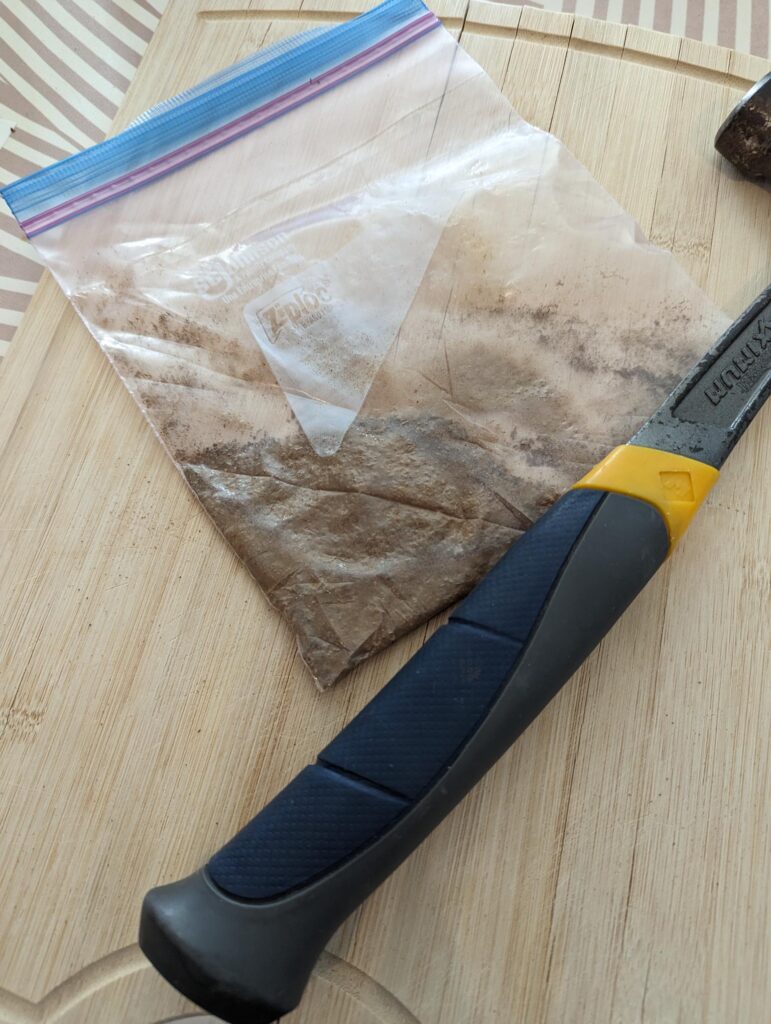 Crushed spices in a bag with a hammer next to them.